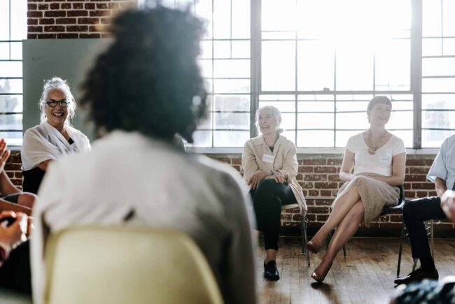 Smiling corporate volunteers sit on chairs in a circle