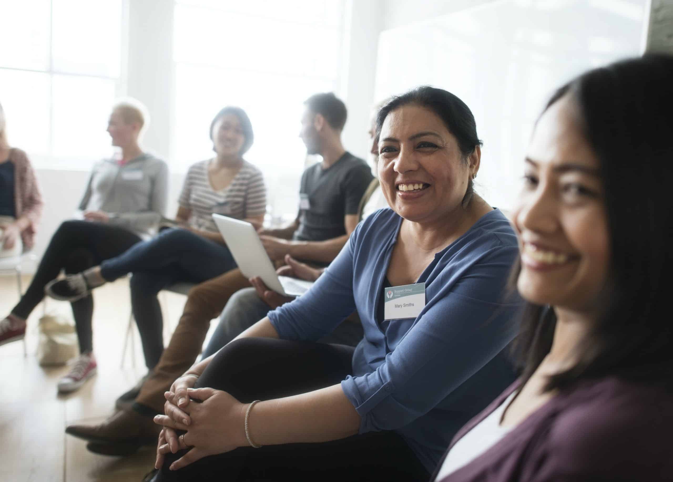 Smiling group participants sit on chairs in a semi-circle