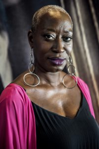 A survivor wearing fuschia lipstick and cardigan faces the camera