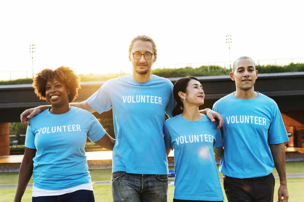 Group of volunteers clad in blue t-shirts walk arm in arm